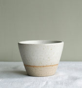 Ceramic bowl with speckled texture on a light surface with a neutral background