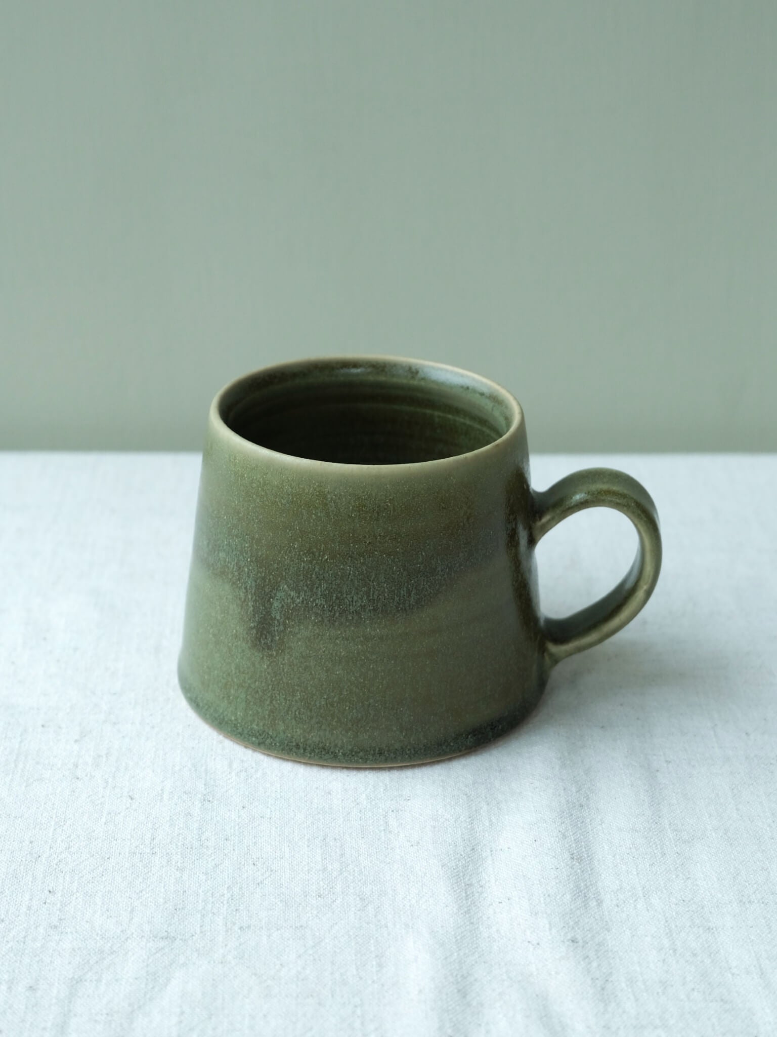 Stoneware taper mug with moss glaze, made by Sophia McEvoy
