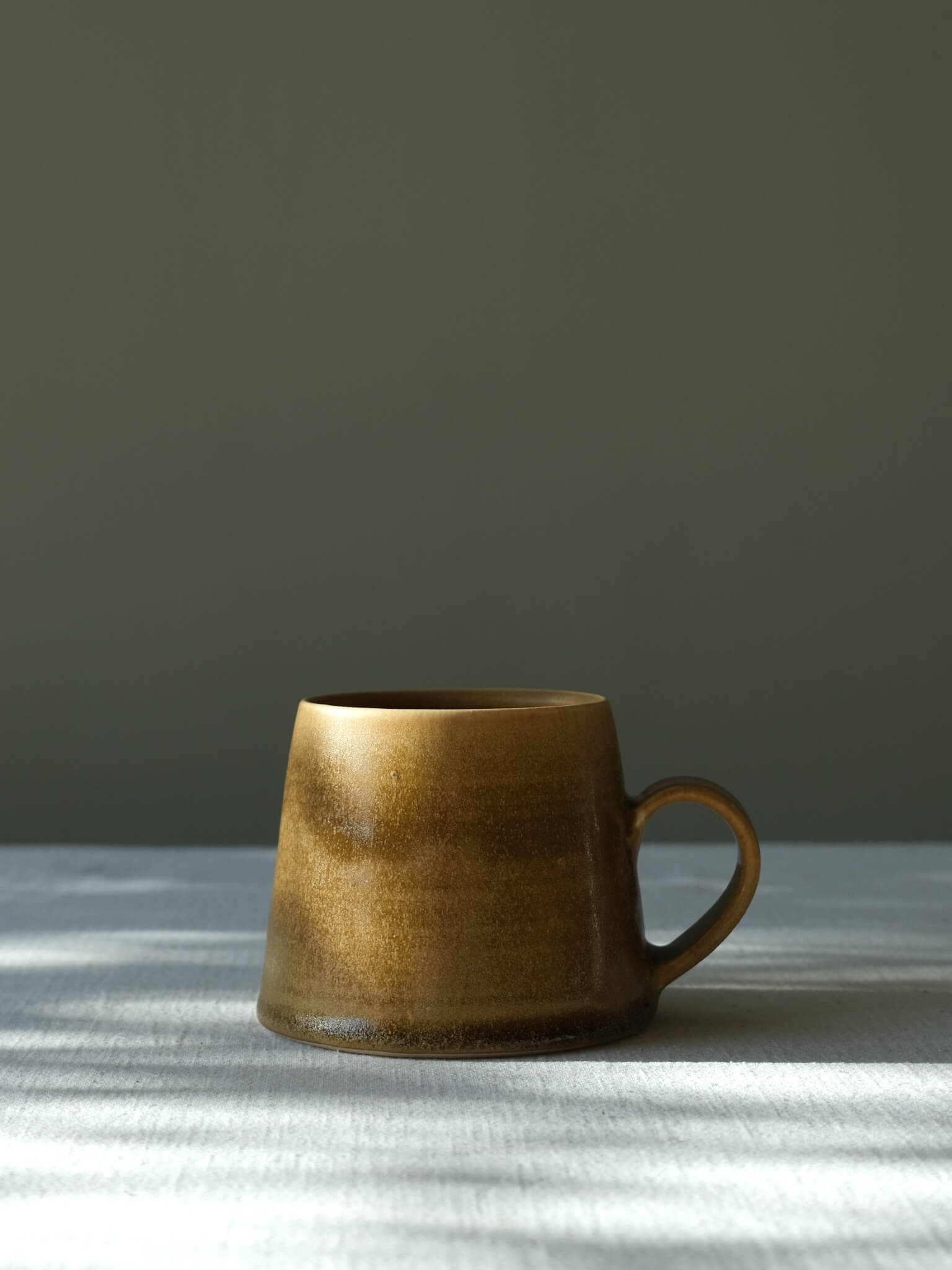Stoneware taper mug with toffee glaze, made by Sophia McEvoy